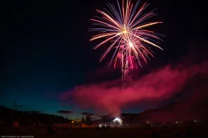 A red, white-gold, and blue firework explodes above Roosevelt Park in Troy, Montana.