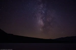 An arm of the Milky Way shines brightly above the Badwater Basin salt flat.