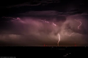 An early nighttime shot of a cloud-to-ground lightning strike over the black landscape of rural North Dakota.
