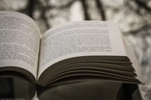 A heavily desaturated still life scene of a favorite book spread open over a reflective surface.