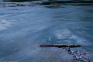 A long exposure of the Kootenai River flowing around a trapped log.