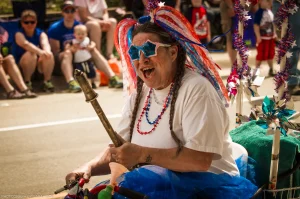 A festively costumed woman rides a water-spraying cart through the 4th of July parade in Troy, Montana.
