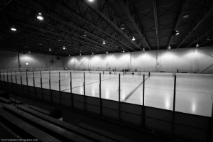 An empty hockey rink in black and white.
